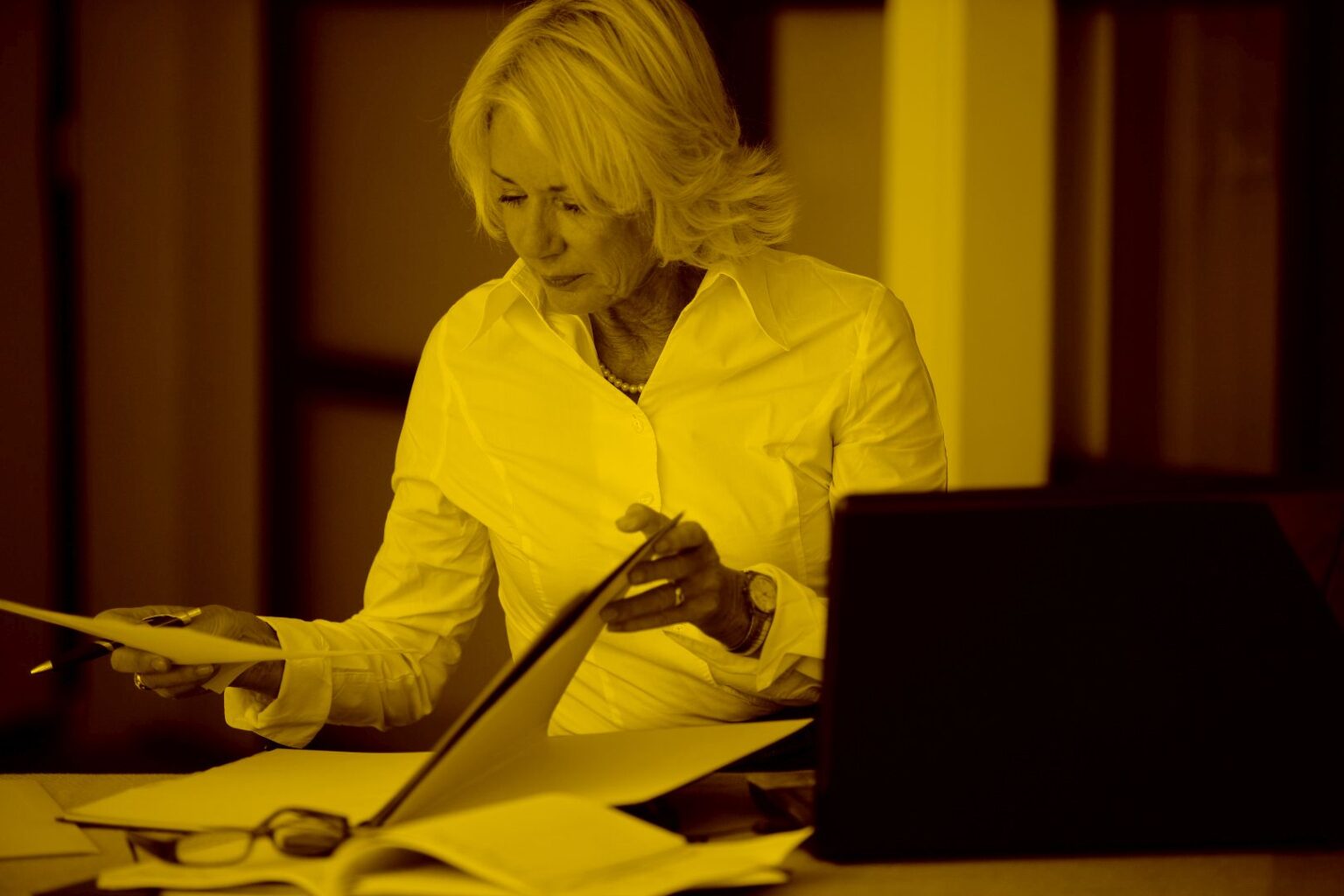 Geschäftsfrau sitzt am Schreibtisch und liest ein Dokument